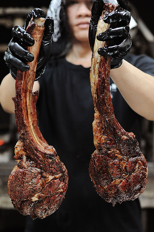 Chef holding 2 Tomahawk steaks vertically